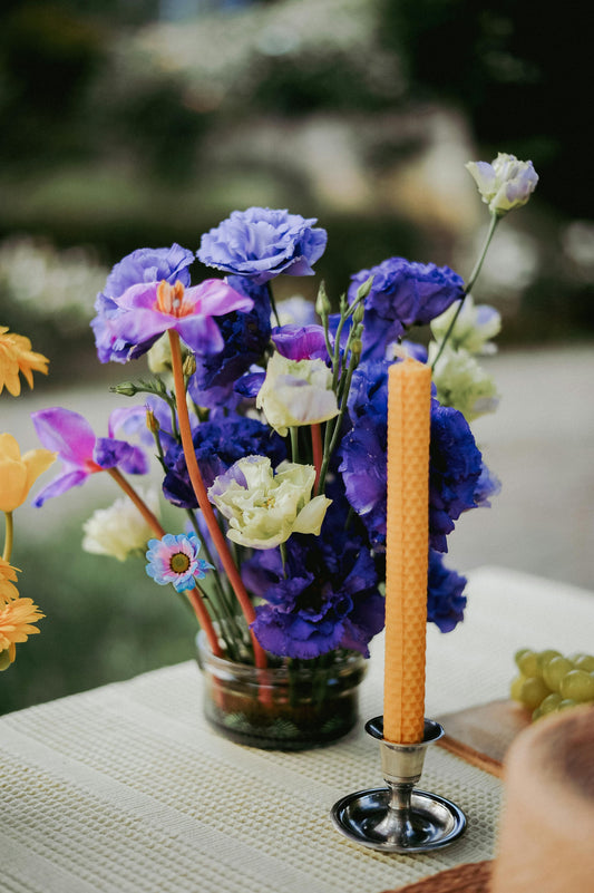 Una vela de miel en un sujeta velas con un ramo violeta deslumbrante 